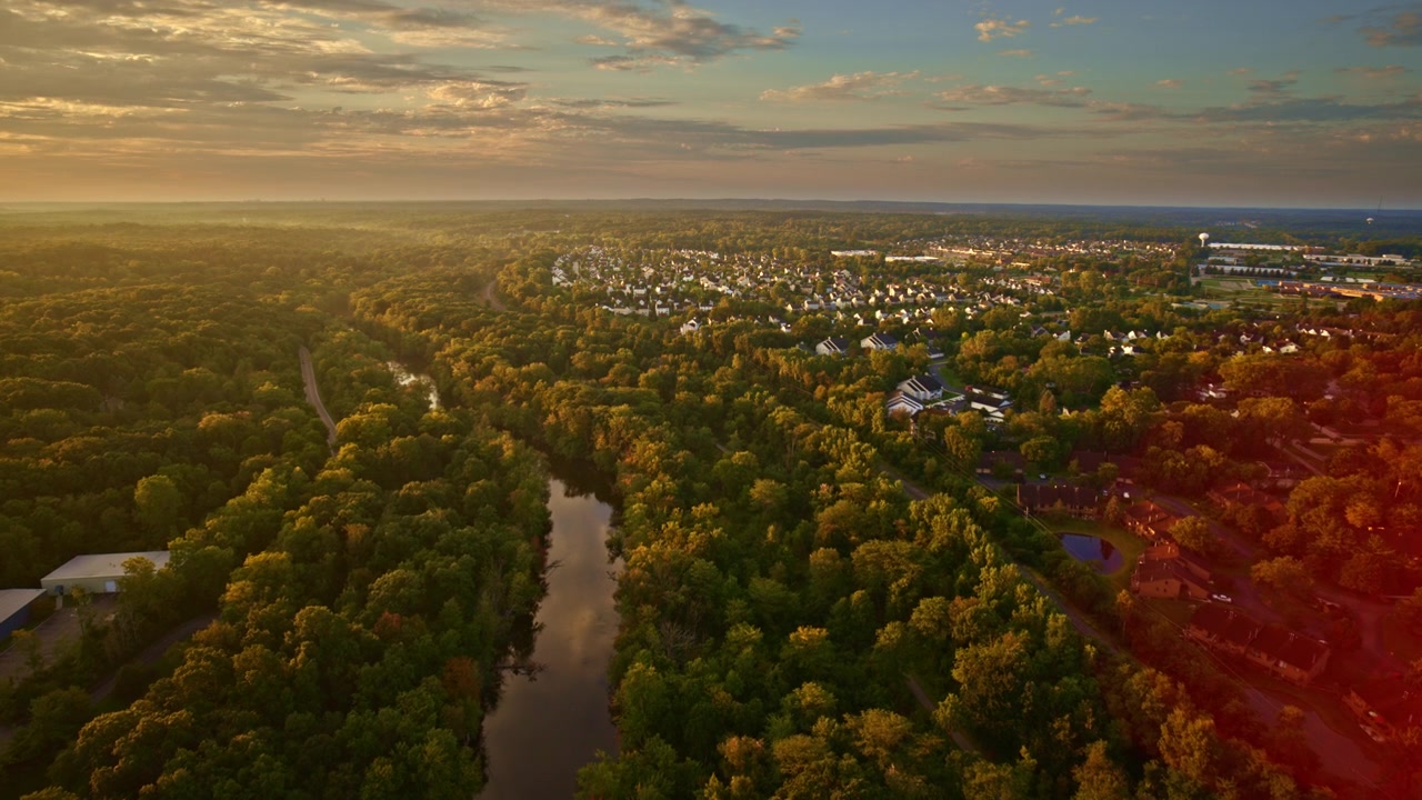 A drone travels above the Huron River on a sunny summer day, approaching Ypsilanti, Michigan.