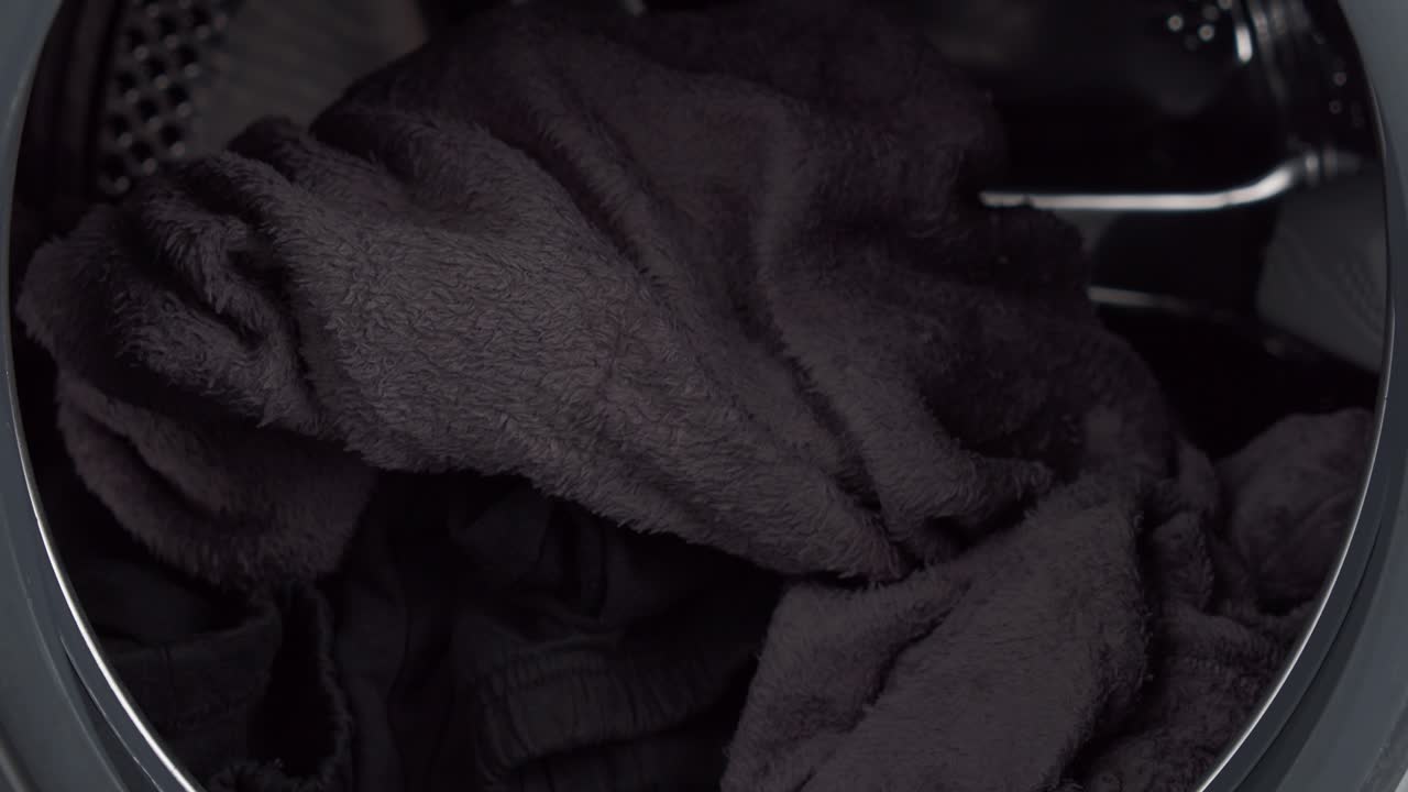 세탁기에서 깨끗한 옷을 꺼내는 사람의 손, 보기를 닫습니다