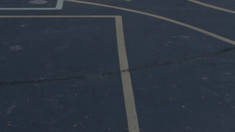 Slow-push-over-lines-for-four-square-and-a-basketball-court-painted-on-a-school-yard-blacktop-outside