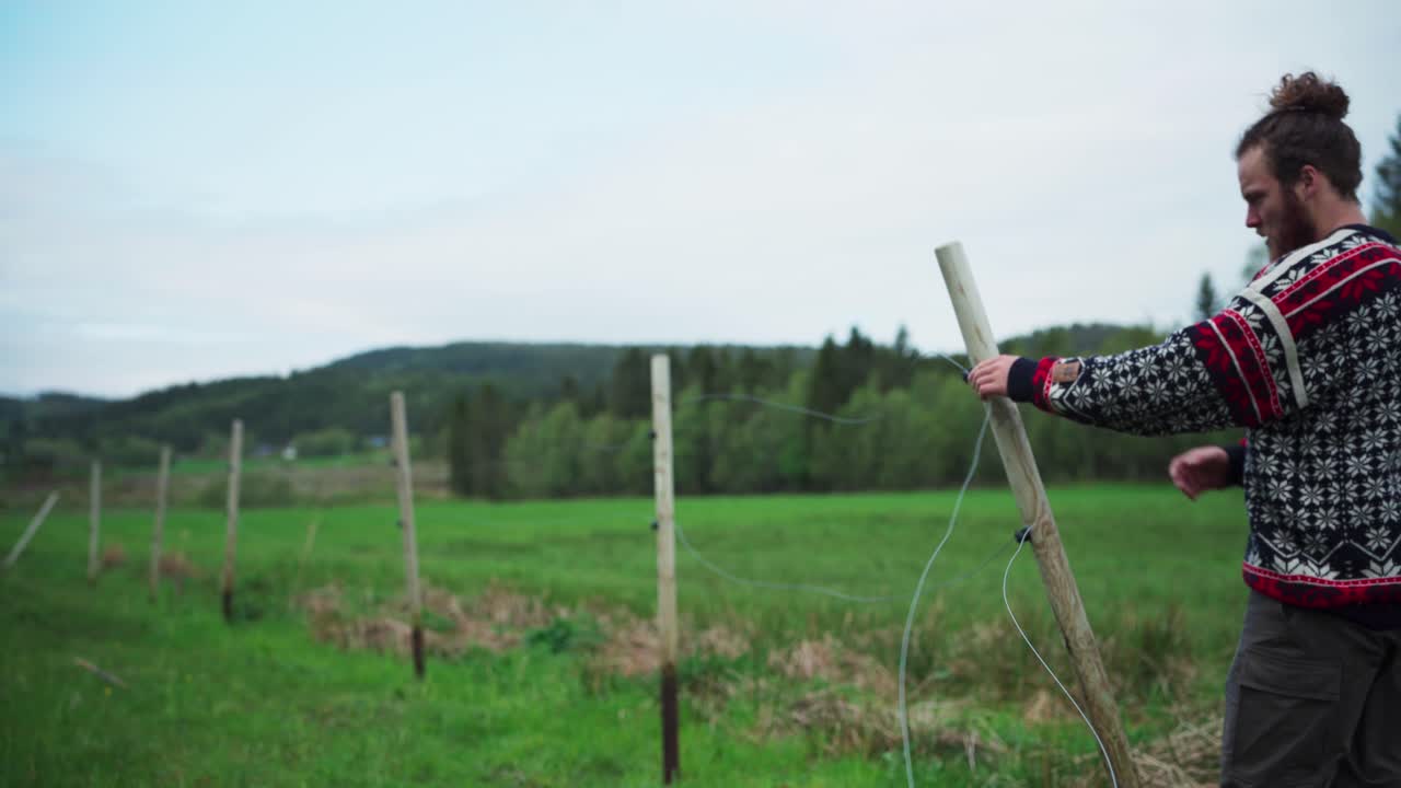 Un uomo sta smontando la recinzione di filo spinato in campagna