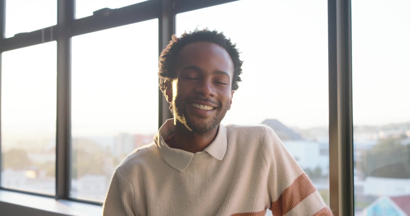 Young Man Using Smartphone and Smiling by Window