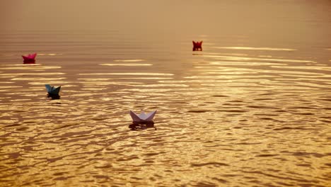 floating paper boats on the water at sunset. paper boat. origami.