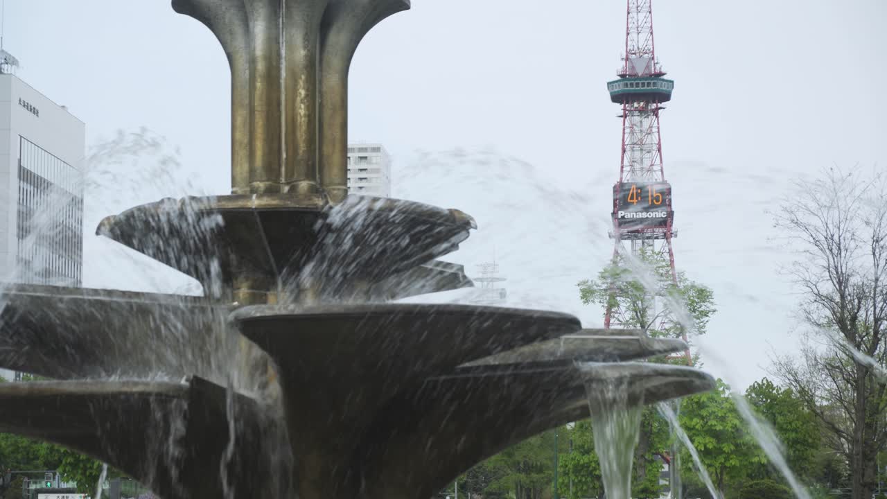 soplando agua en la fuente en el parque odori con la torre de televisión sapporo en el fondo en hokkaido, japón