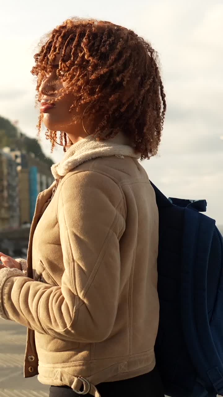 Donna con capelli ricci che indossa una giacca in spiaggia