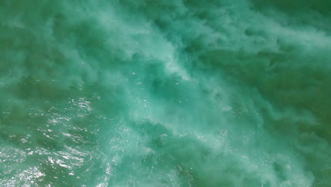 aerial overhead view of waves and foam of the portuguese atlantic breaking on the shore