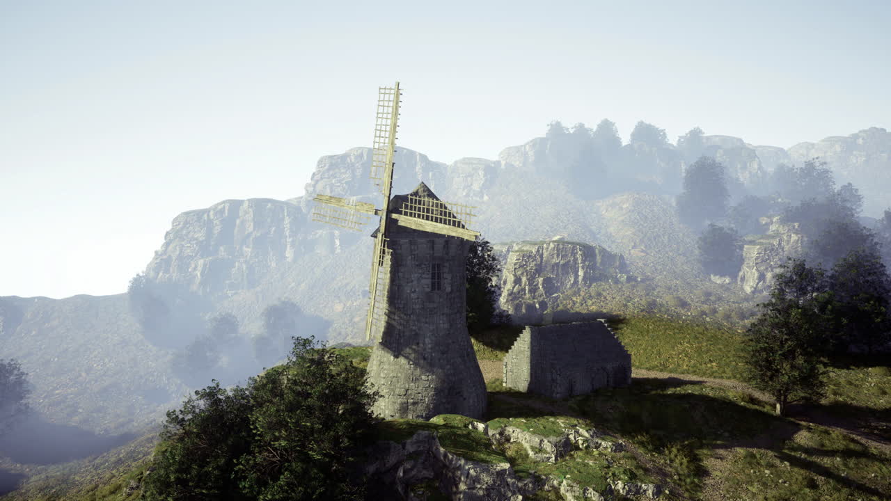 Historic windmill stands on a hilltop surrounded by mountains and trees