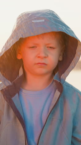 rain-soaked and weary boy on riverbank. child heart aches with weight of abandonment with spirit dampened by relentless rain. drowned by downpour