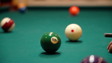 slow motion billiards person shoots 15 ball on pool table with green felt using the cue ball and a black carbon fiber cue stick using stun or stop close up with depth of field