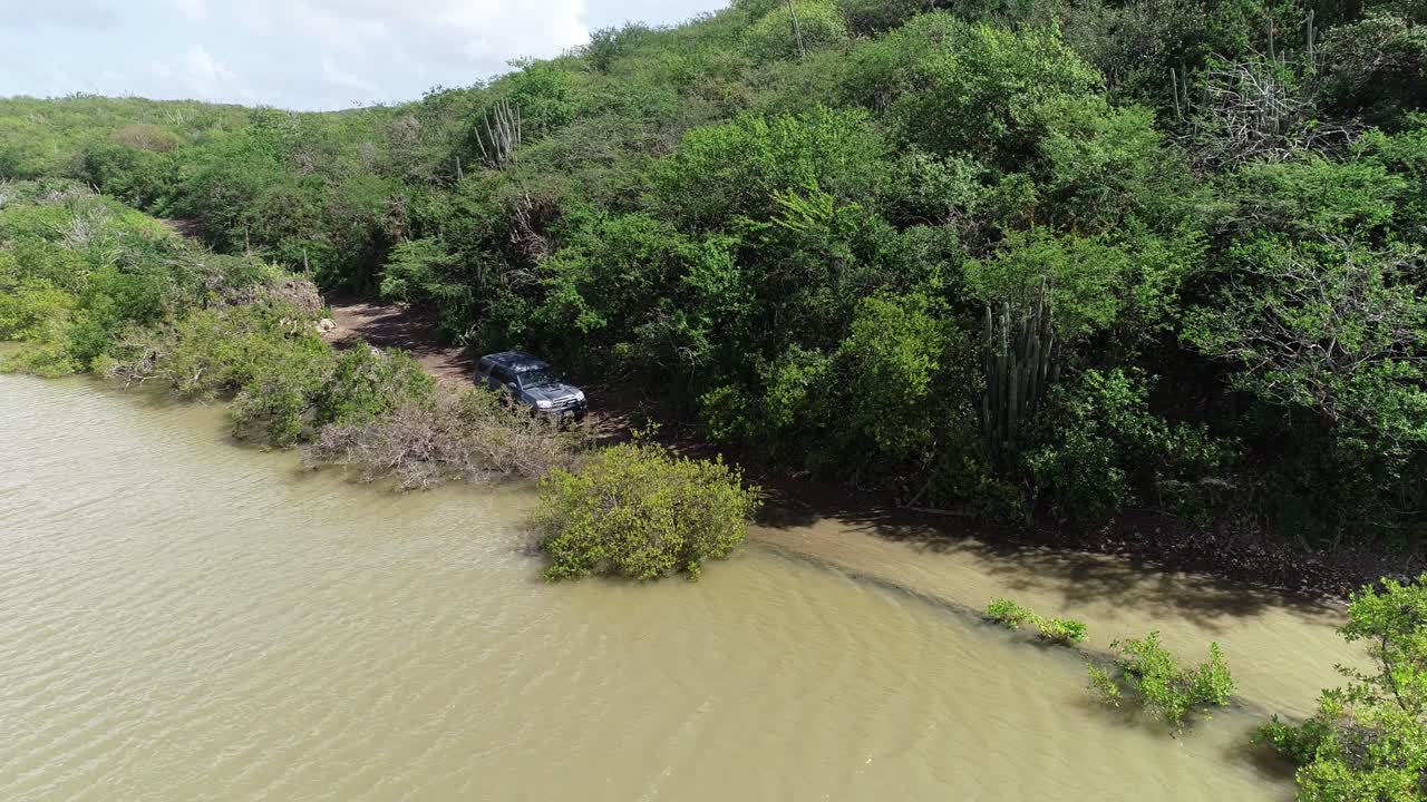 conducción de automóviles fuera de la carretera en la costa rocosa olas rompiendo vista de drones