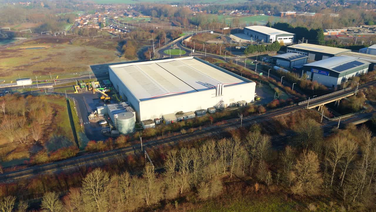 Vista aerea tramite drone di un grande capannone industriale situato accanto a un'importante linea ferroviaria a Rugby, Regno Unito.