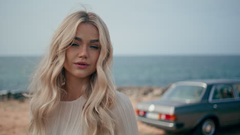 blonde woman by the ocean with a vintage car