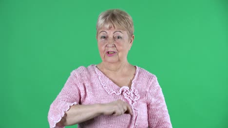 retrato mujer mayor escucha atentamente, asenta la cabeza con aprobación, señala con un dedo sí, tienes razón, exactamente. abuela de cabello gris en un suéter rosa en la pantalla verde en el estudio. cerca