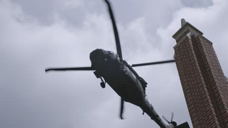 Toma-En-Cámara-Lenta-Del-Helicóptero-Blackhawk-Sobrevolando-Un-Edificio-En-El-Cielo