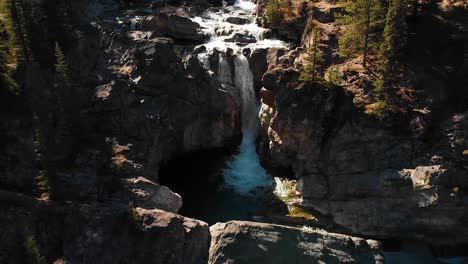 Drone-view-revealing-a-flowing-waterfall-in-a-Canadian-forested-landscape