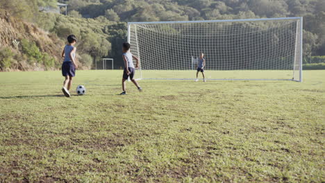 playing soccer on school field, kids kicking ball towards goal net