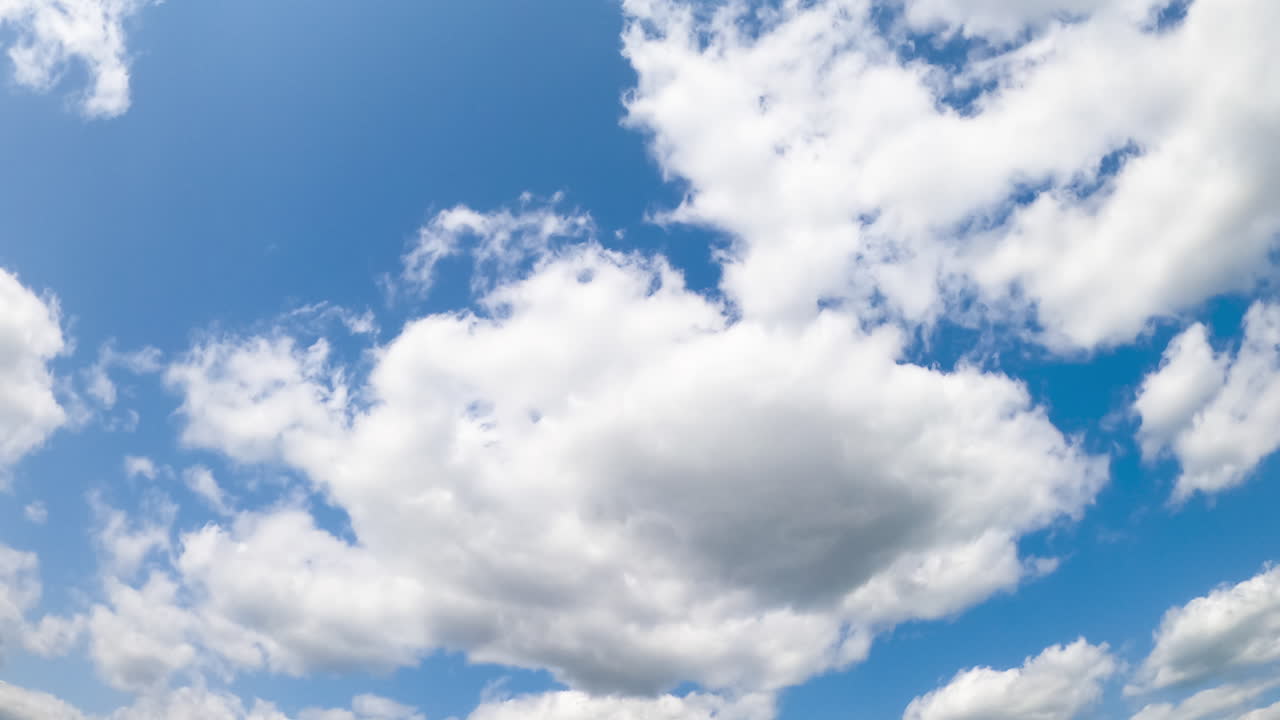Wind blowing and white clouds quickly change shapes. Sun lighting the cloudscape. Low angle view. Timelapse.