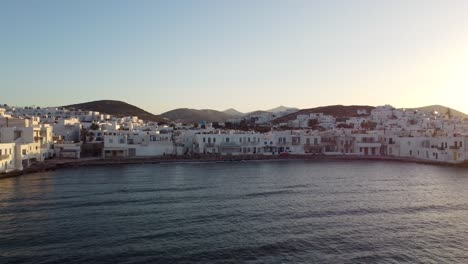 Asombrosa-Foto-De-Acercarse-A-La-Pintoresca-Playa-Pequeña-Y-Al-Pueblo-Naoussa-De-Paros-Durante-La-Puesta-De-Sol-De-Verano-En-Grecia-Desde-El-Mar