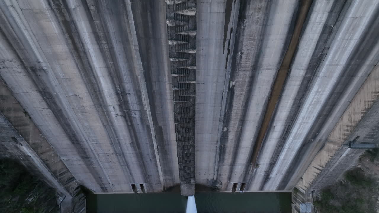 Aerial view looking down at Sau reservoir concrete wall rising over hydroelectric dam structure