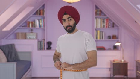 hombre indio sikh feliz midiendo la cintura usando cinta de pulgada