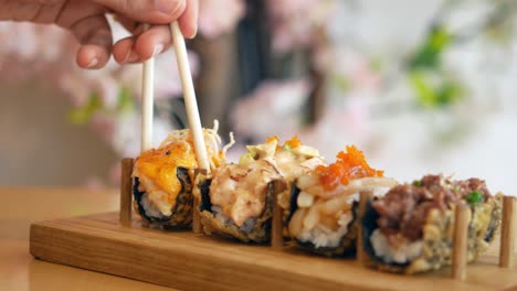 comiendo varios rollos de sushi fritos con palillos