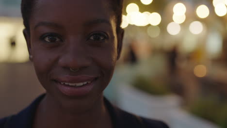 Primer-Plano-Retrato-De-Una-Hermosa-Mujer-De-Negocios-Afroamericana-Mirando-La-Cámara-Sonriendo-Confiada-Usando-Un-Anillo-En-La-Nariz-En-El-Fondo-De-La-Ciudad-Por-La-Noche-Bokeh-Claro