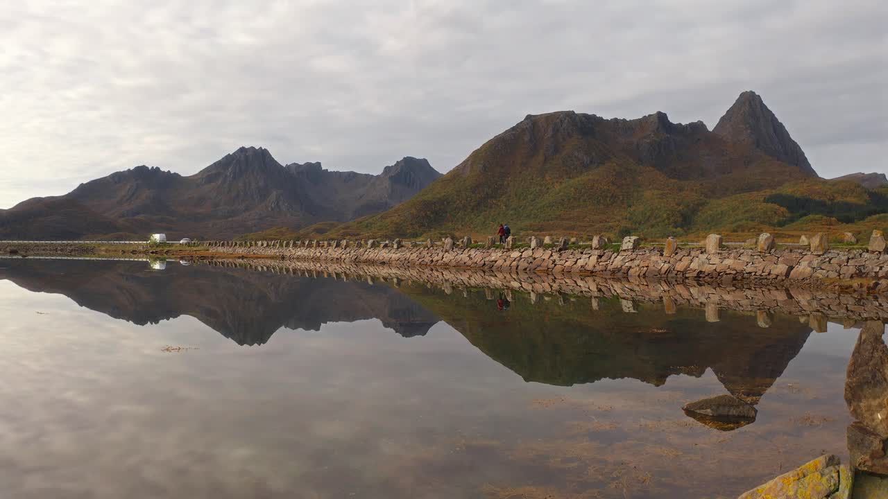 Peaceful scenic view of Vestarelen with tourists and a dog walking along the shore