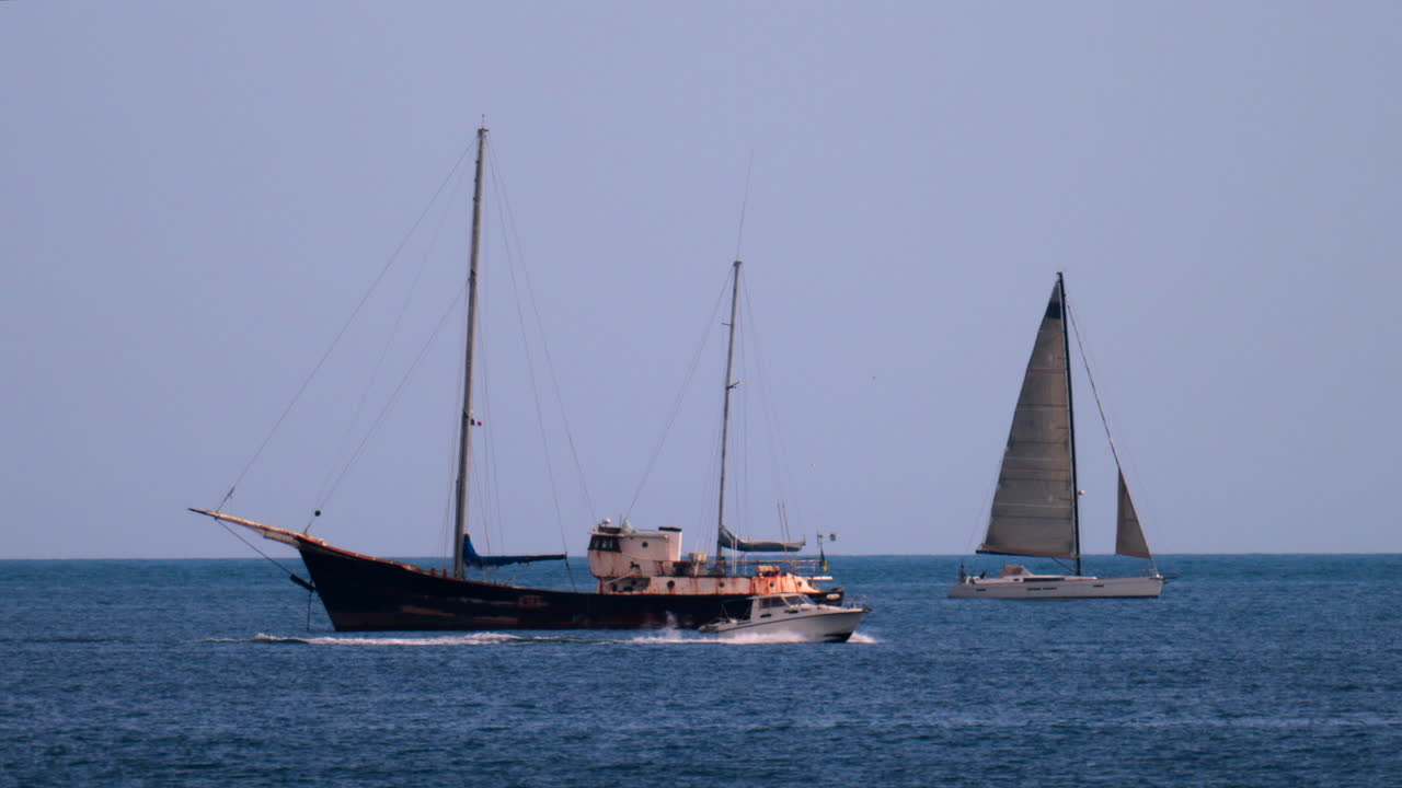 Distant view of a rusty boat moving near other boats on the sea in the south of France, on a cloudy day