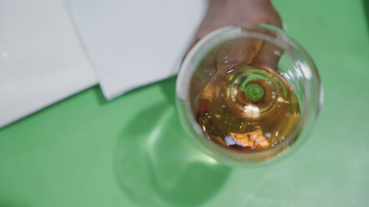 Elegant romantic toast. Green surface supporting glass of wine. Refined scene featuring glass of wine on surface. An intimate scene portraying wine glass with amber liquid on green surface