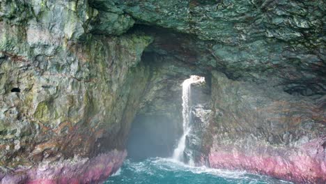 4k hawaii kauai navegando en el océano de tiro medio alejándose de una cascada en una cueva
