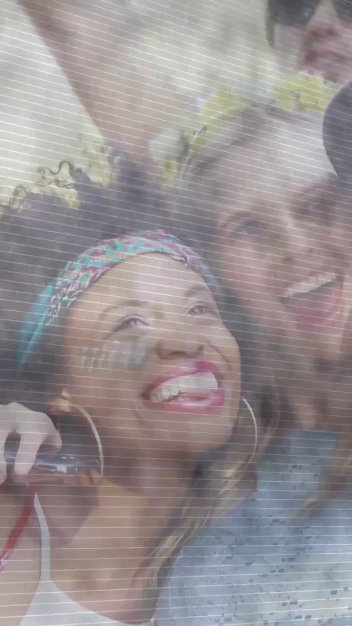 Headbanded woman holding phone, leading friends in festival selfie, capturing joy for social media