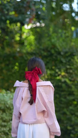 girl with red bow in a park