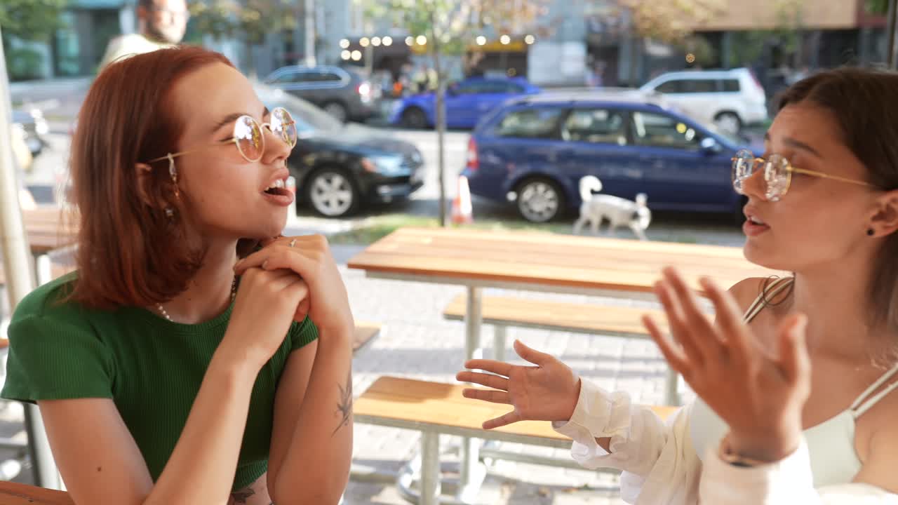 두 친구 가 야외 카페 에서 대화 를 즐기고 있다