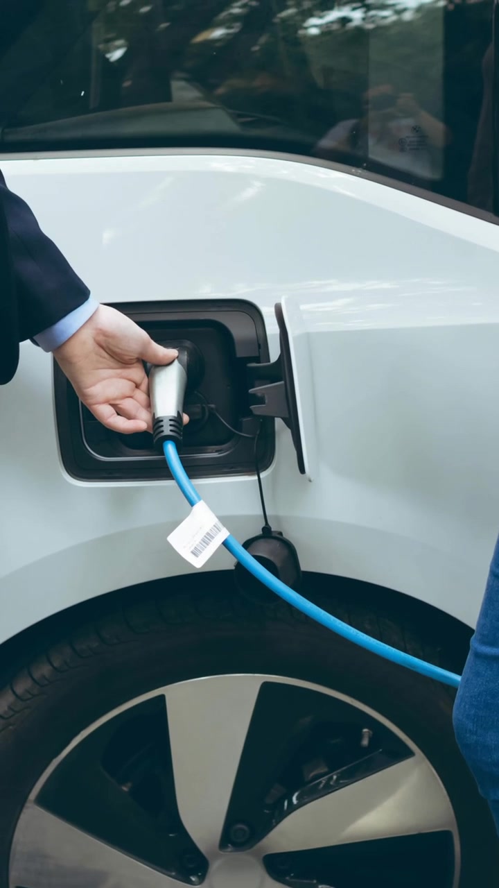 Elektrikli arabayı şarj eden beyaz erkek ve kadının orta bölümü.