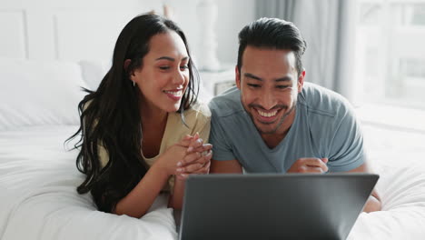 Couple,-relax-and-laugh-on-bed-with-laptop-to