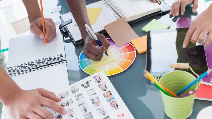Diverse group of fashion designers working in fashion studio with tablet and images on table