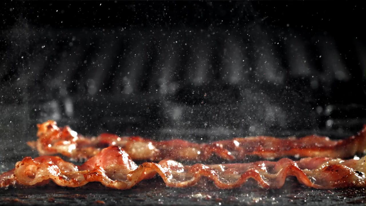 Strisce di pancetta croccante che sfrigolano e friggono su una padella calda
