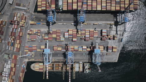 Static-overhead-aerial-hyperlapse-of-shipping-containers-being-moved-onto-ships