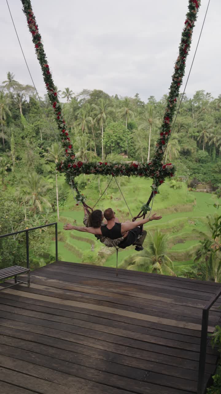 Magical kiss on swings in Bali junlge, back view of romantic couple