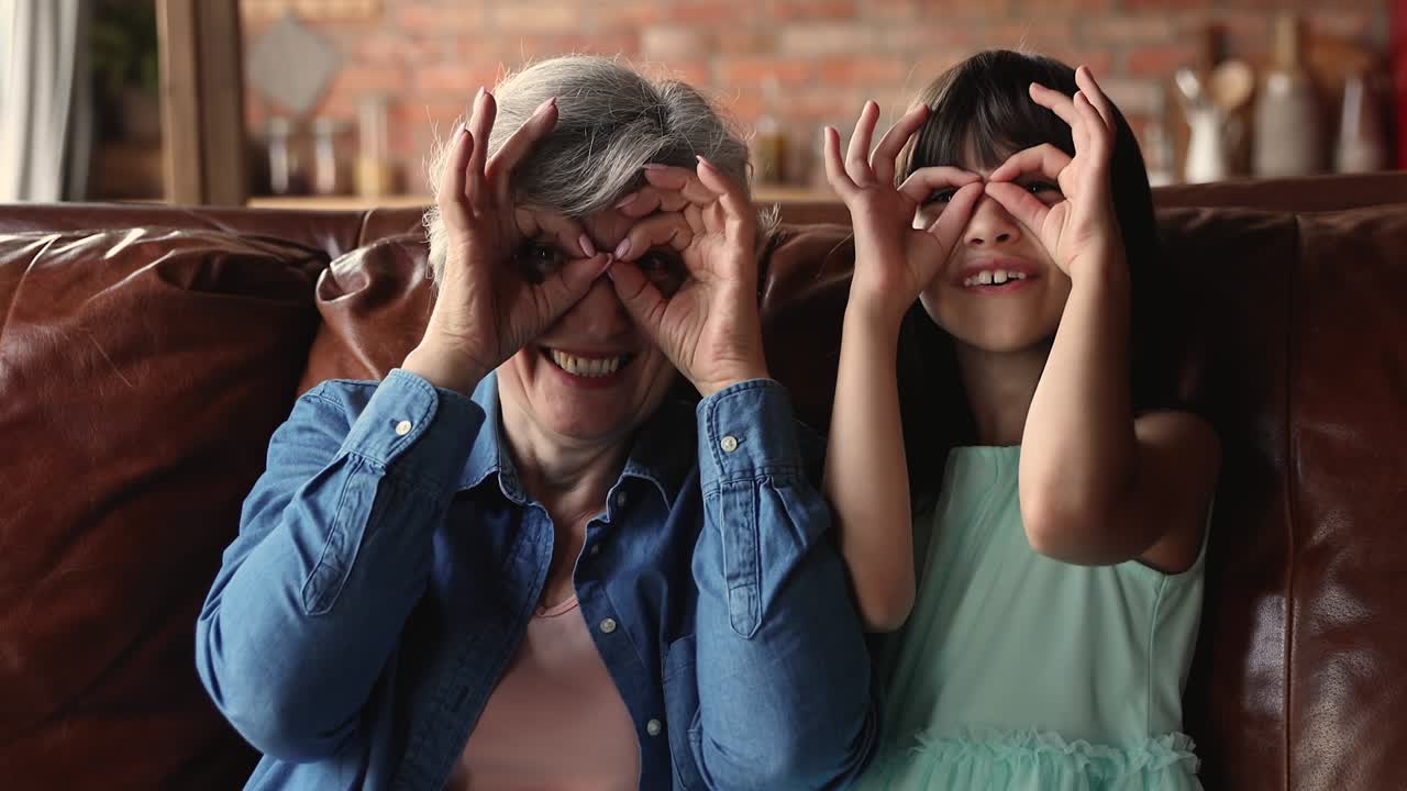abuela su pequeña nieta haciendo forma binocular con los dedos