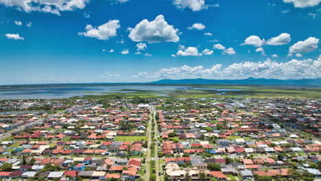 Aerial-hyperlapse-of-a-summer-day-with-blue-sky-and-clouds-in-a-small-city-with-a-river-and-mountains-in-the-background