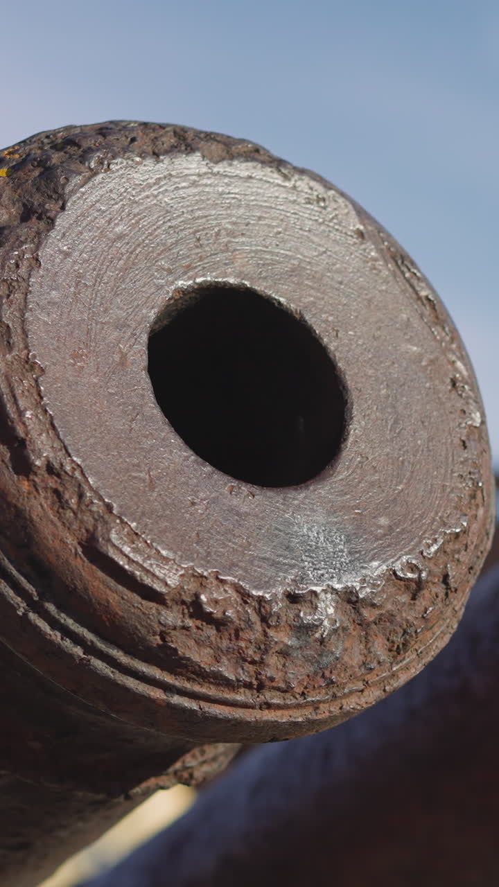 Large rusty cannon muzzles against blue sky with white haze. Ancient military equipment covered with rust stands in city park on sunny day closeup