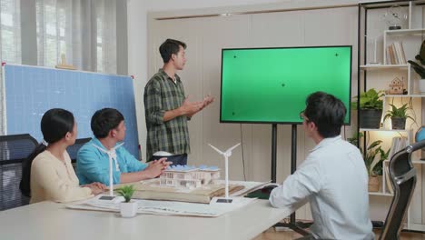 ingeniero hombre asiático con célula solar presentando sobre la pantalla verde de la televisión en la oficina