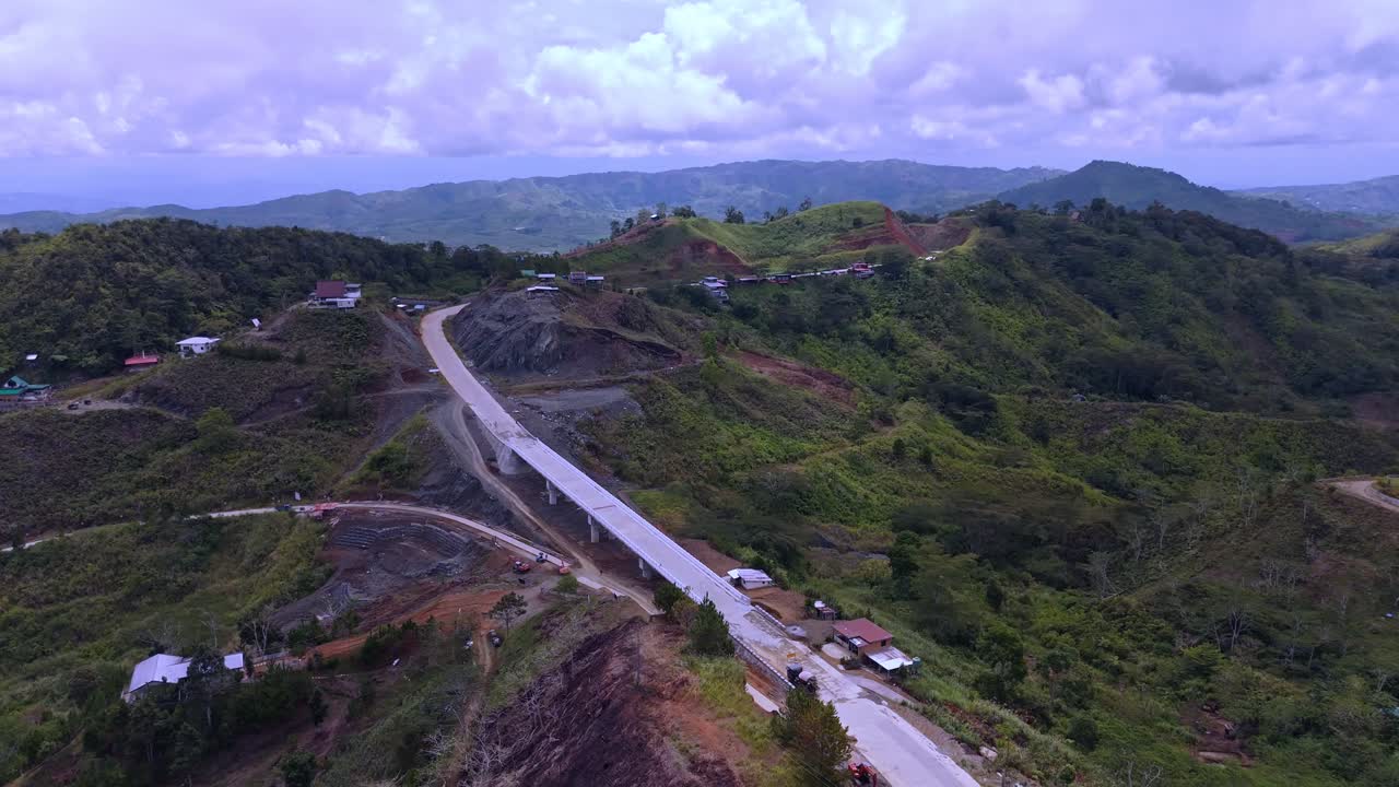 drone shot over a rugged mountain landscape showing a newly constructed, elevated highway section or bridge. Focuses on civil engineering, infrastructure development, and transportation in challenging