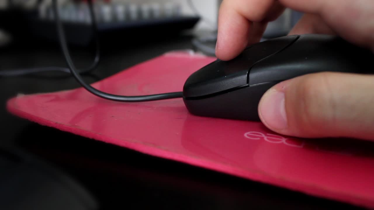 Close-Up of Hand Clicking and Scrolling Computer Mouse on Red Pad