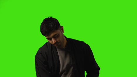 Young-Man-Answering-Call-On-Mobile-Phone-Standing-Against-Green-Screen-Studio-Background-2