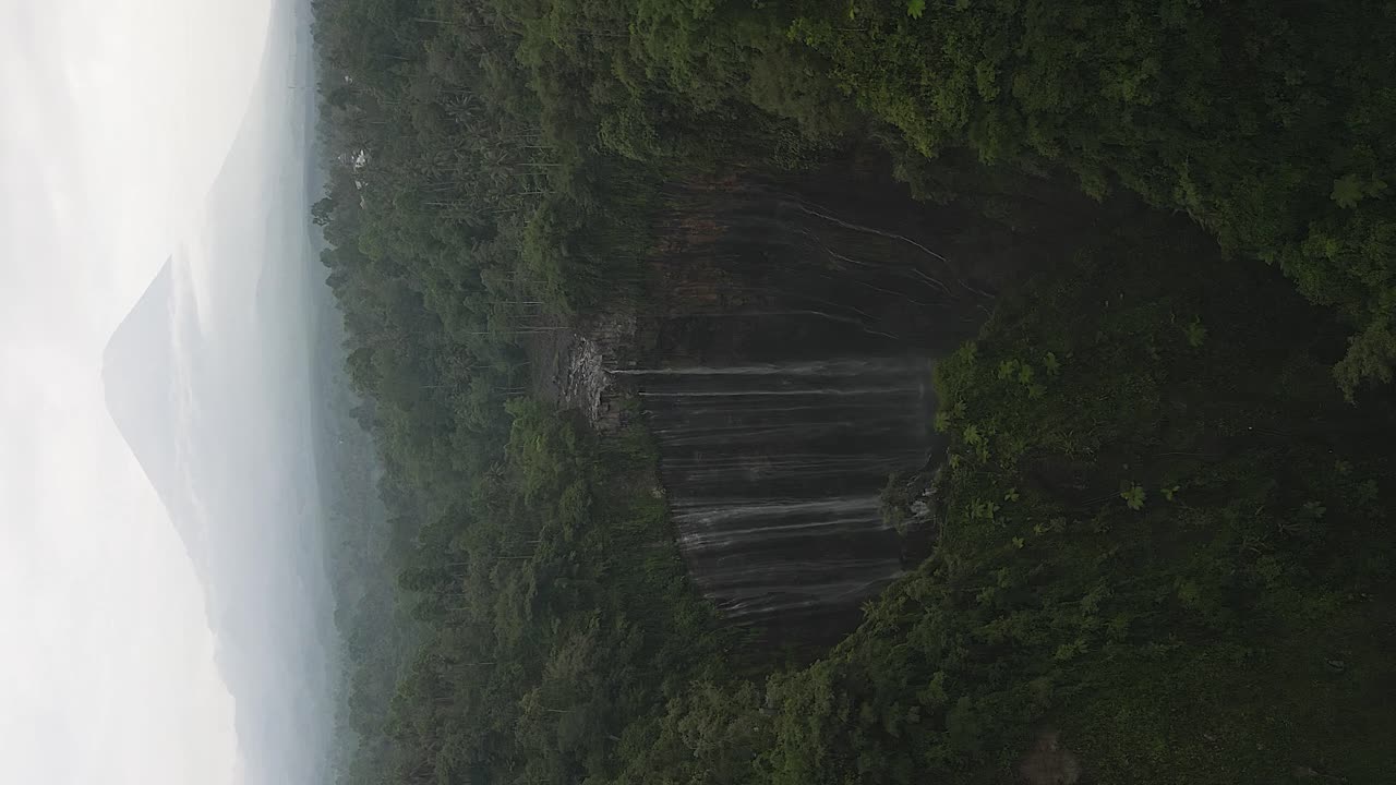 formato vertical: impresionante cascada de tumpak sewu con el cono del volcán de java