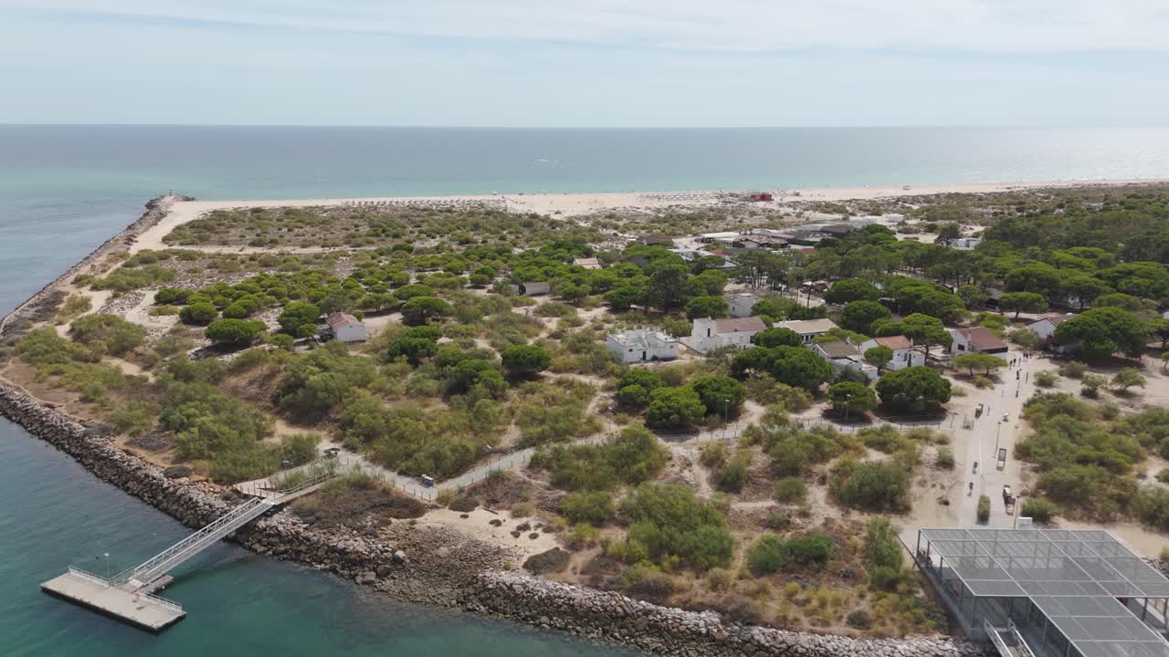 Vista aerea panoramica con drone che immortala il terminal dei traghetti e una fluida discesa aerea sull'isola di Tavira, Portogallo