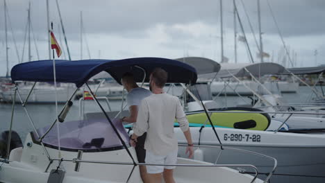 two men boarding a boat at a marina
