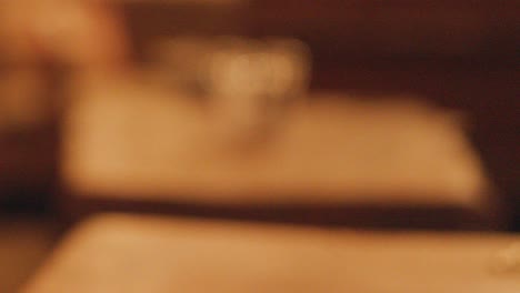 a pint glass of dark stout beer sits on a wooden table in a softly lit pub. the camera slowly pulls focus away, creating a blurred background