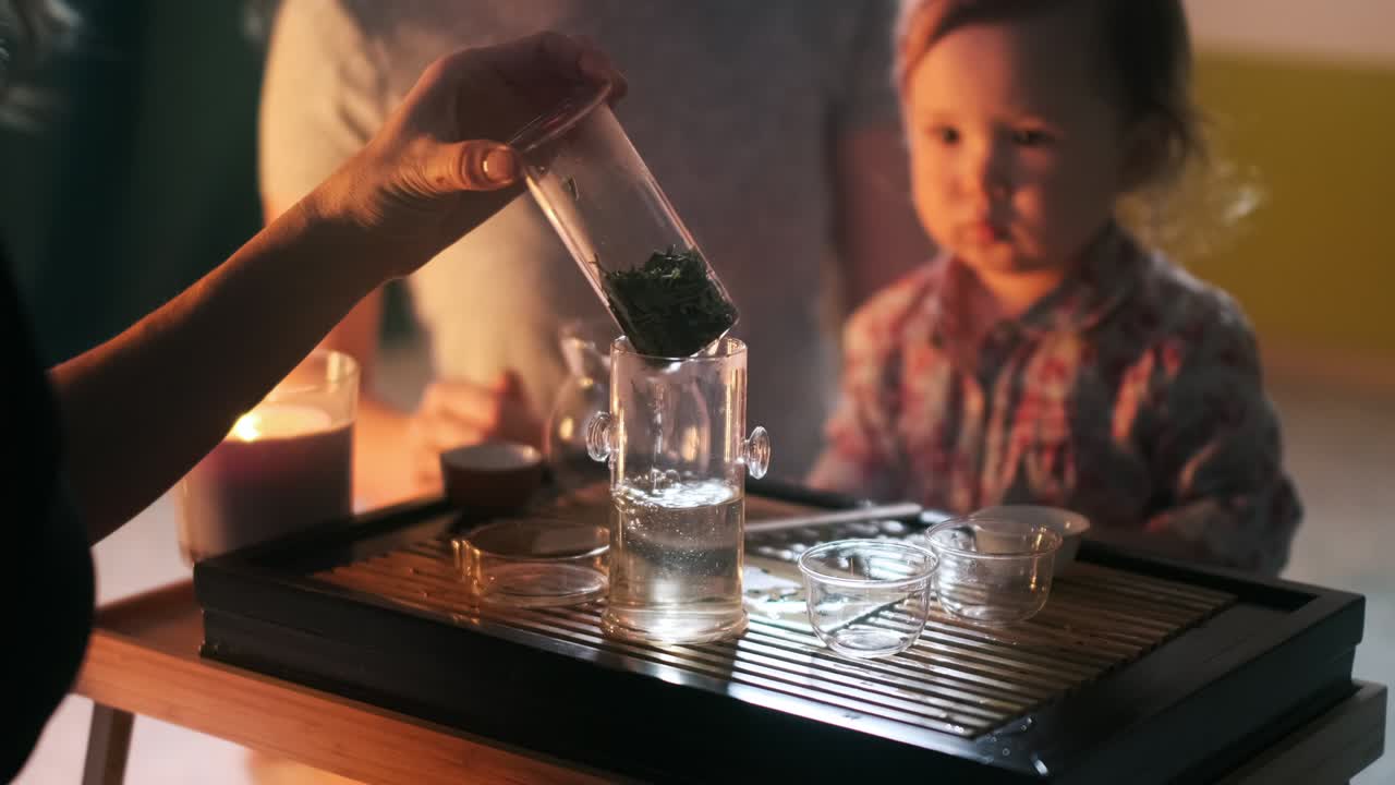 cinemagraph de la ceremonia del té con el bebé. la familia realiza la ceremonia del café en casa con la niña. cinemograph con el té vertiendo en la olla